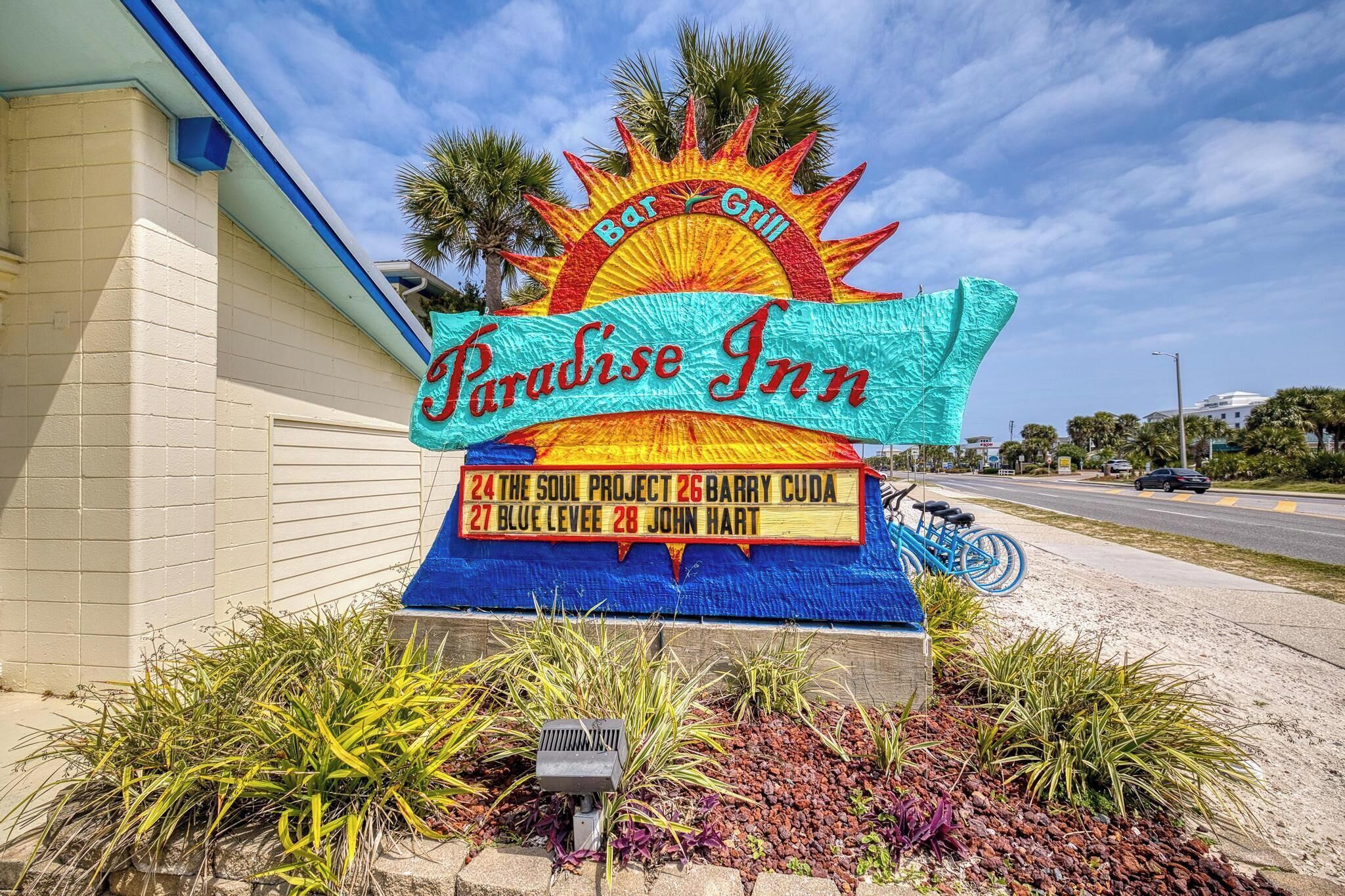 Schild für Paradise Inn mit Sonnenelement, das Zimmernummern und -bezeichnungen auflistet.