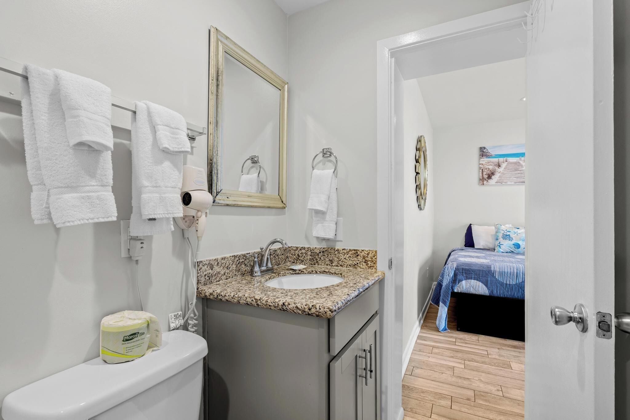 A bathroom with a sink, mirror, towels, and a toilet.
