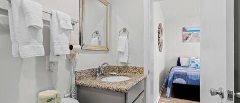 A bathroom with a sink, mirror, towels, and a toilet.