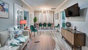 A modern living room with a sofa, a round coffee table, a dining table with chairs, a TV mounted on the wall, and a decorative lamp. - Walk to the Neuse River! New Bern Vacation Rental (New Bern)