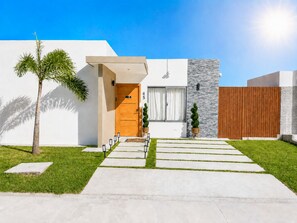 A modern house with a wooden door, a stone wall, and a wooden fence. - Stylish Family Villa with Private Pool & Yard (Verón Punta Cana (D. M.).)