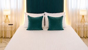 Une chambre d’hôtel avec un grand lit, deux tables de chevet avec des lampes, un climatiseur fixé au mur et des rideaux légers.