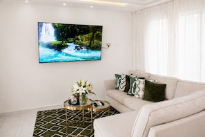 Een woonkamer met een bank, een salontafel, een schilderij en een vaas met bloemen.