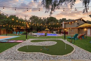 A backyard with a pool, lawn, and string lights. - Meadow Circle Estate - Pool, Spa & Outdoor Games (San Antonio)