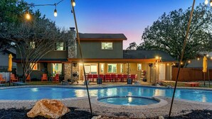 Una propiedad residencial con piscina, mobiliario exterior e iluminación con luces colgantes.