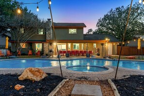 A residential property with a swimming pool, outdoor seating, and string lights. - Meadow Circle Estate - Pool, Spa & Outdoor Games (San Antonio)