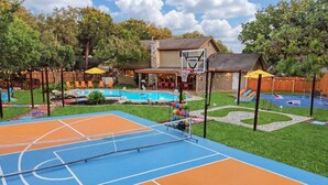 Una cancha de baloncesto al aire libre con piscina y sillones de descanso.