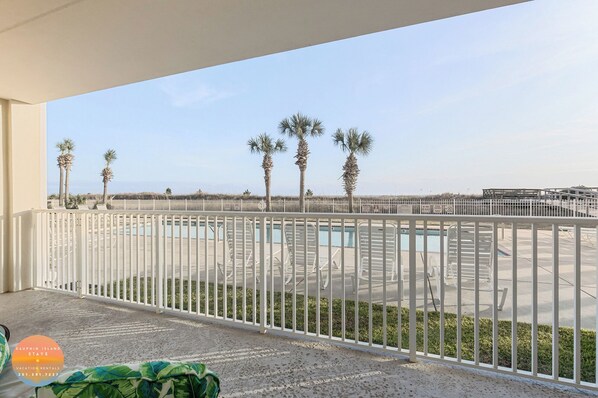 Un balcón con vista a una piscina y palmeras.