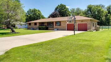 Front exterior of a brick ranch home with a large lawn and two-car garage.