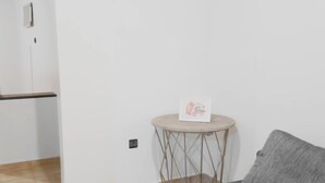 A living room with a grey sofa, a small round table with a picture frame, and a tiled floor. - Apartment 5 minutes from the stadium (Rabat)