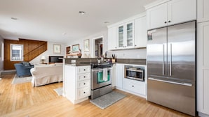 Une cuisine moderne avec des meubles blancs, des appareils électroménagers en acier inoxydable et un plancher en bois.