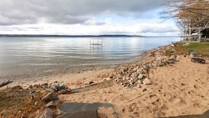 Une plage avec un kiosque, une eau cristalline et une côte qui s’étend au loin.