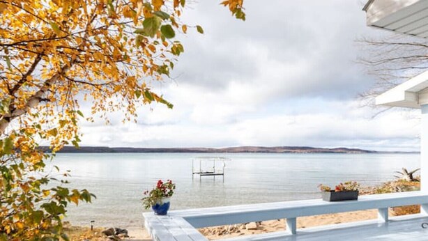 Une terrasse en bois avec un chemin de pierre menant à un point de vue donnant sur un lac paisible et des collines lointaines.