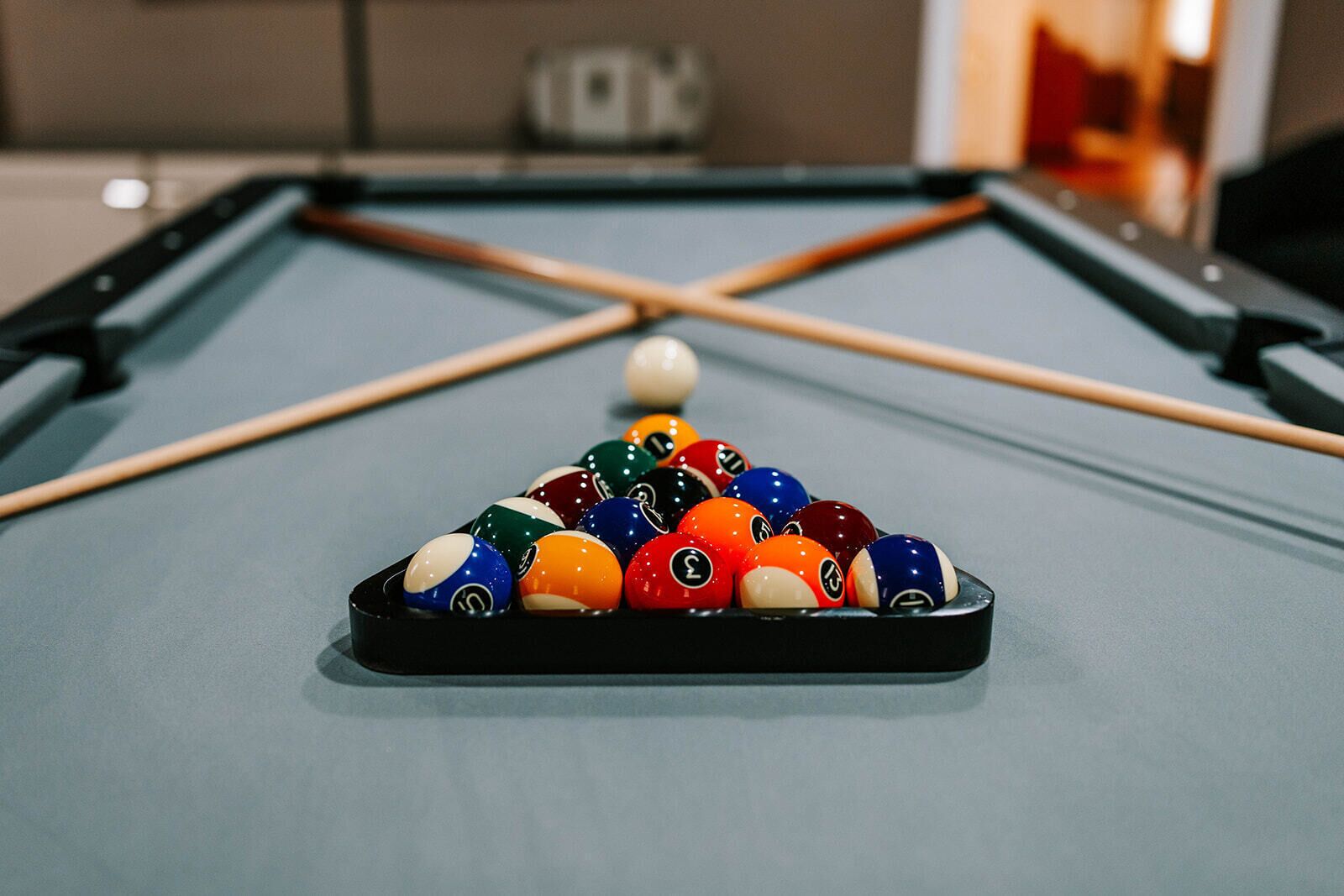 A pool table with a set of billiard balls and a cue stick.