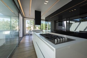 A modern kitchen with a central island, large windows, and a view of the outdoors.