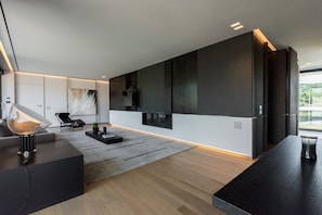 Un salon moderne avec un canapé, une table basse, un téléviseur fixé au mur et une grande fenêtre.
