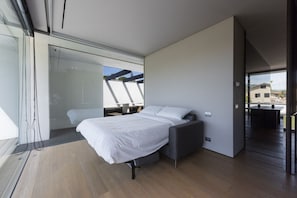 A modern bedroom with a bed, a grey bench, and a glass door leading outside. - Villa Bilor Luxe by MMega (Subbiano)