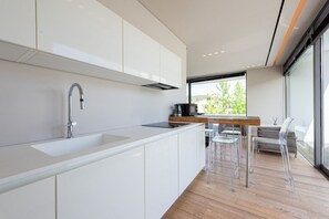 A modern kitchen with white cabinets, a stainless steel sink, and a wooden dining table with clear chairs. - Villa Bilor Luxe by MMega (Subbiano)
