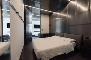 A modern hotel room with a large bed, a desk, and a chair. There is a sliding door leading to a balcony. - Villa Bilor Luxe by MMega (Subbiano)
