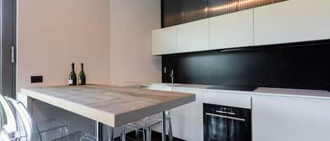 Una cocina moderna con una mesa de madera, sillas transparentes y un horno empotrado.