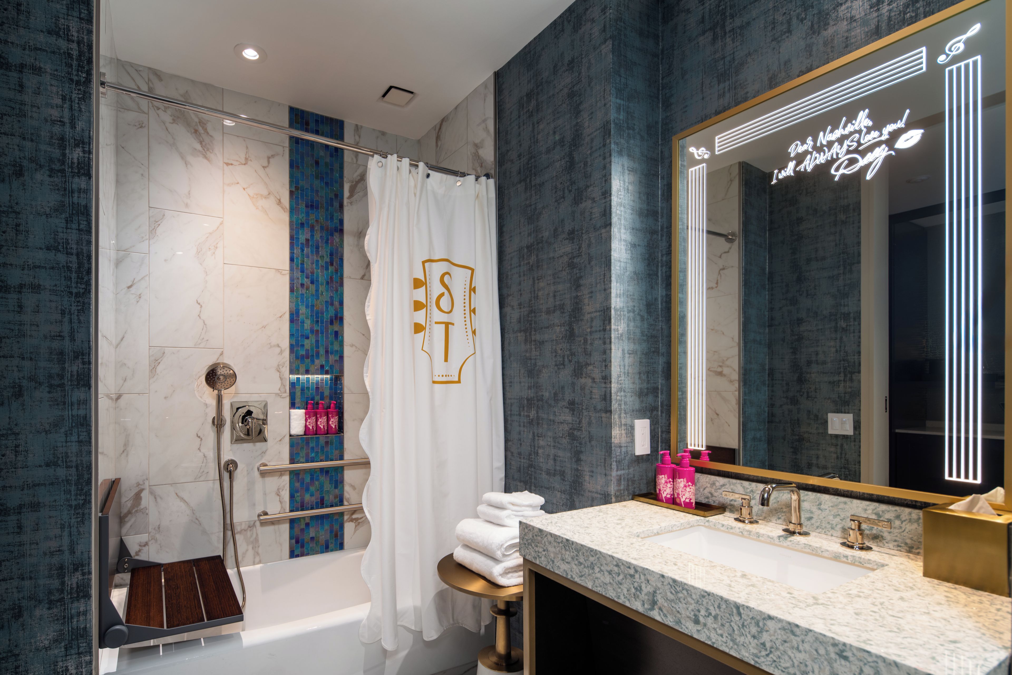 Un baño moderno con ducha de mármol, un espejo grande y un tocador con lavabo.