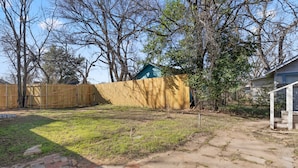 Ein Garten mit Holzzaun, einer kleinen Gartenhütte und einem Pflasterweg.