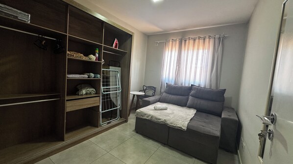 A room with a bed, a wardrobe, a small table, and a window with curtains.