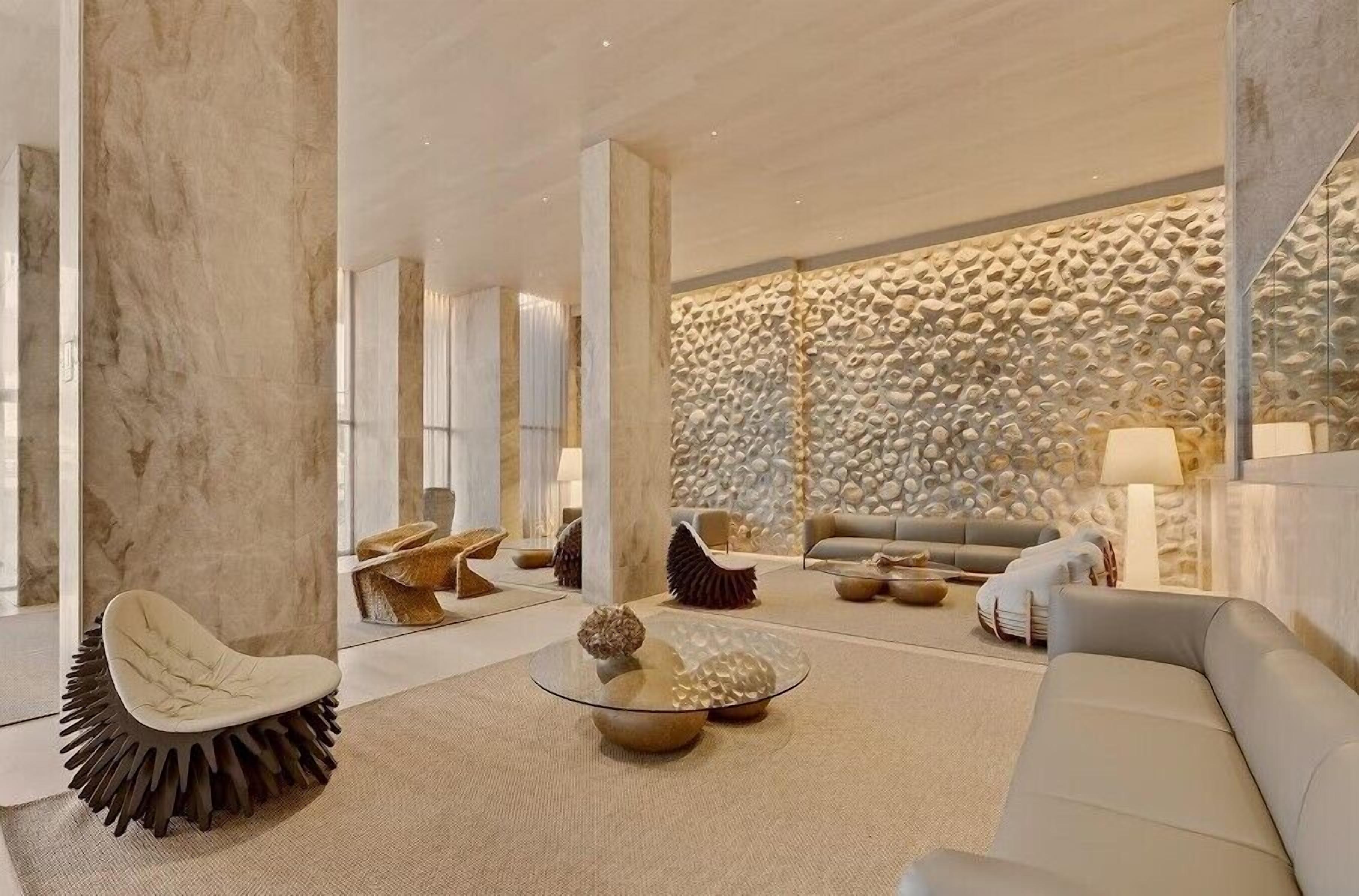 Een modern interieur met een stenen muur, een ronde glazen salontafel en een witte bank.