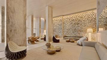 Een modern interieur met een stenen muur, een ronde glazen salontafel en een witte bank.
