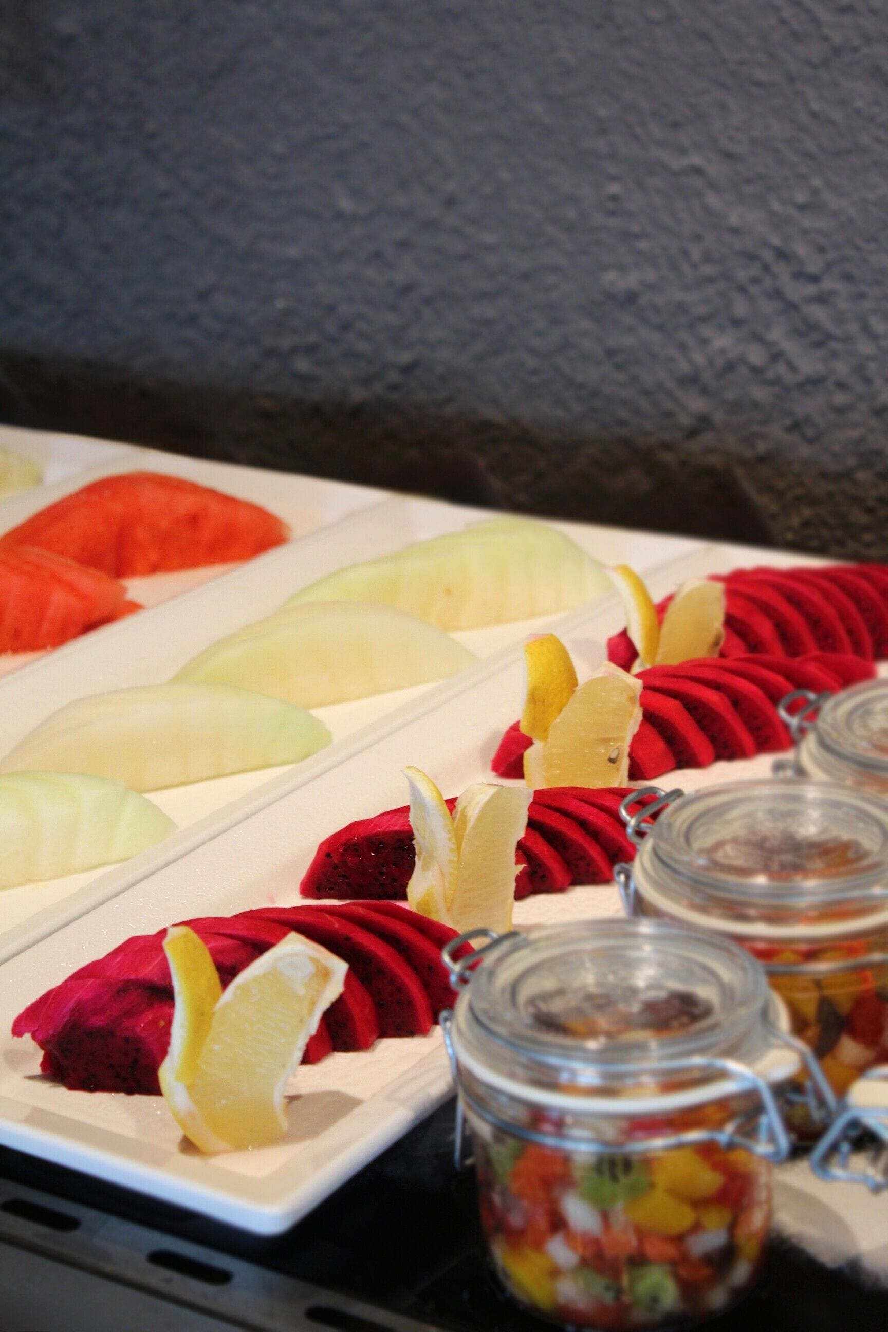 Een buffet met diverse soorten fruit en een assortiment jam in potten.