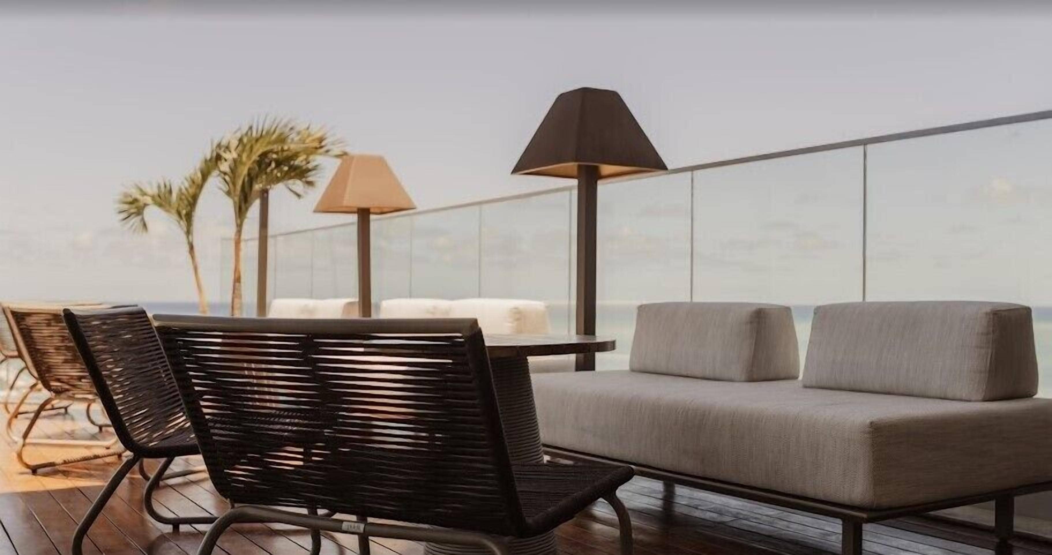 Una terraza en la azotea con un sofá, sillas, una mesa y dos lámparas.