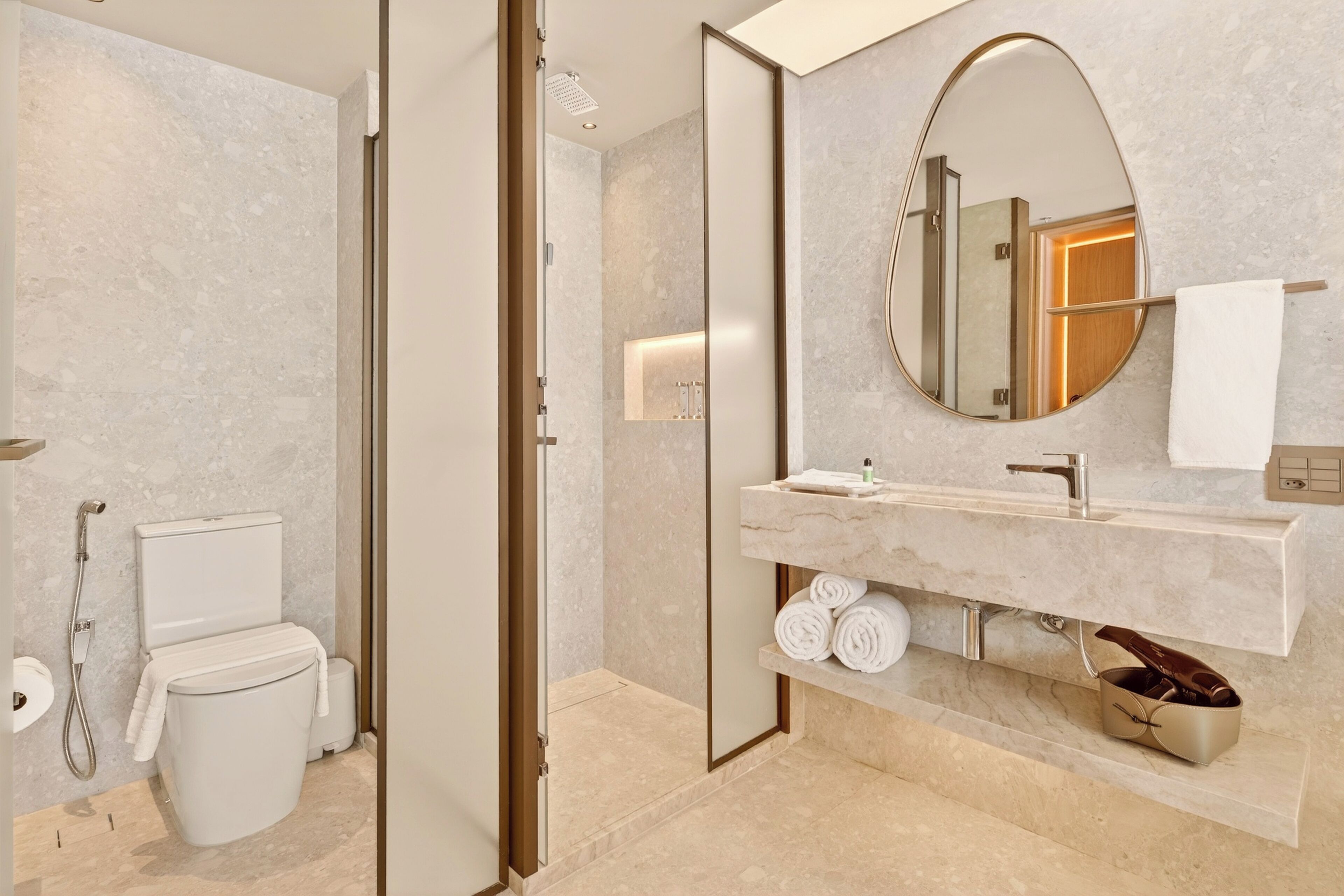 A modern bathroom with a toilet, shower, and vanity with a mirror.
