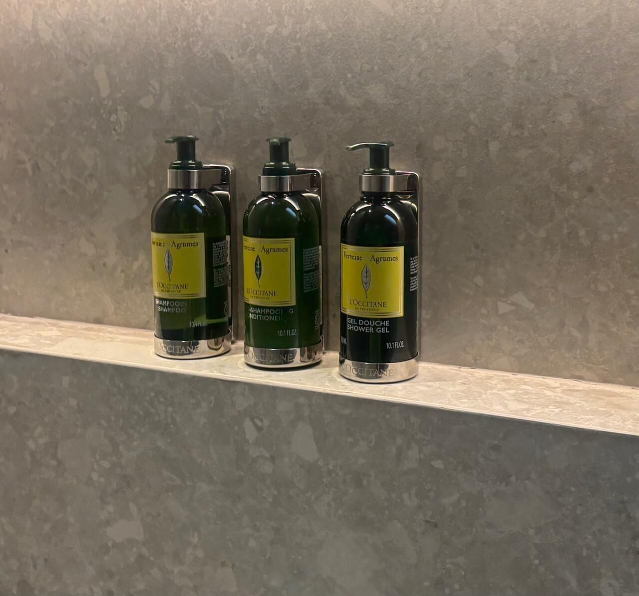 Tres botellas de champú y acondicionador sobre una estantería.