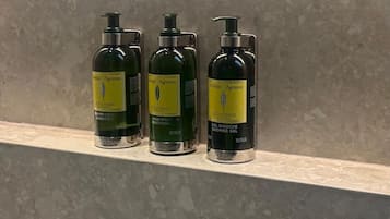 Tres botellas de champú y acondicionador sobre una estantería.