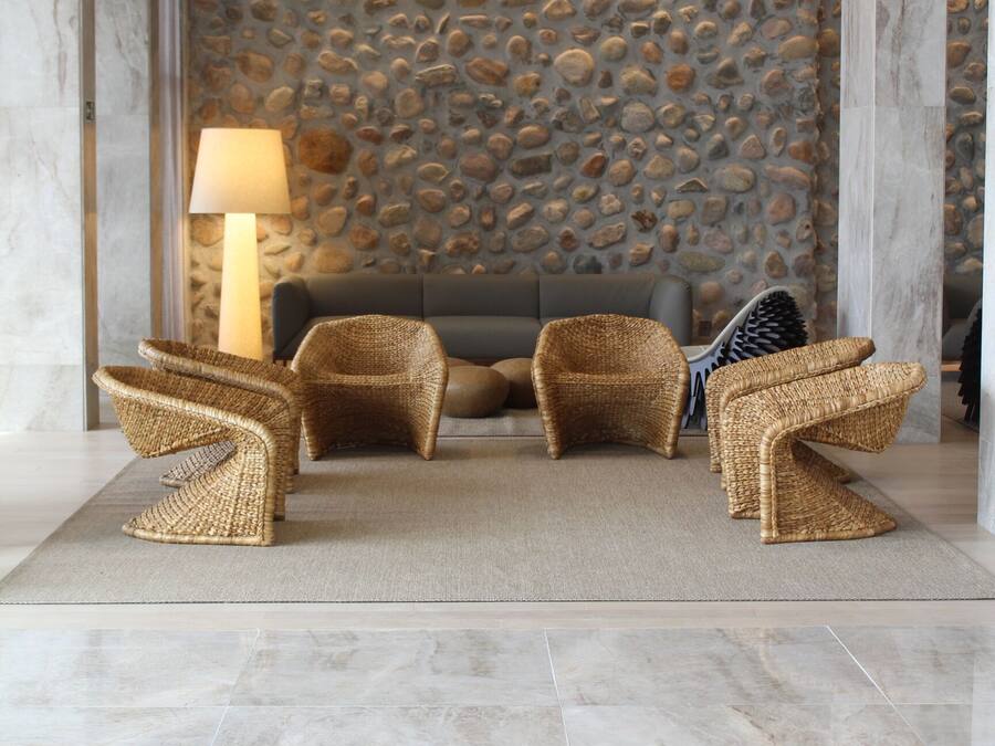 Un hall con pared de piedra, un sofá y sillones de mimbre.