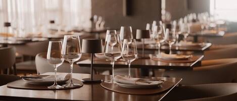 Un restaurante con mesas dispuestas para comer, con copas de vino y platos.