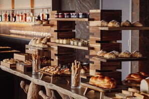 Un bufé con diversas opciones de panadería y pastelería exhibidas sobre bases de madera.