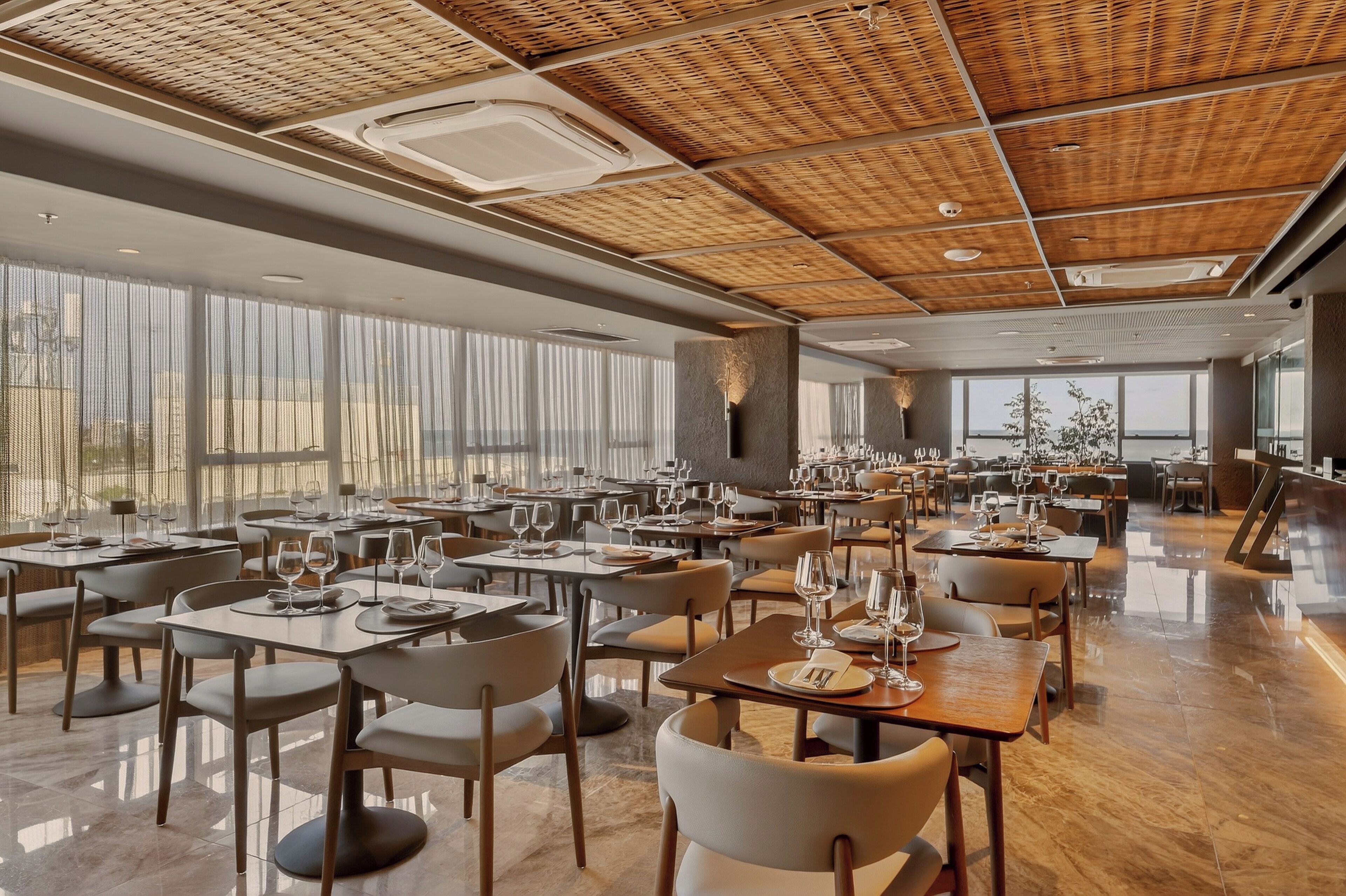 A spacious restaurant with high ceilings, large windows, and a modern interior design.