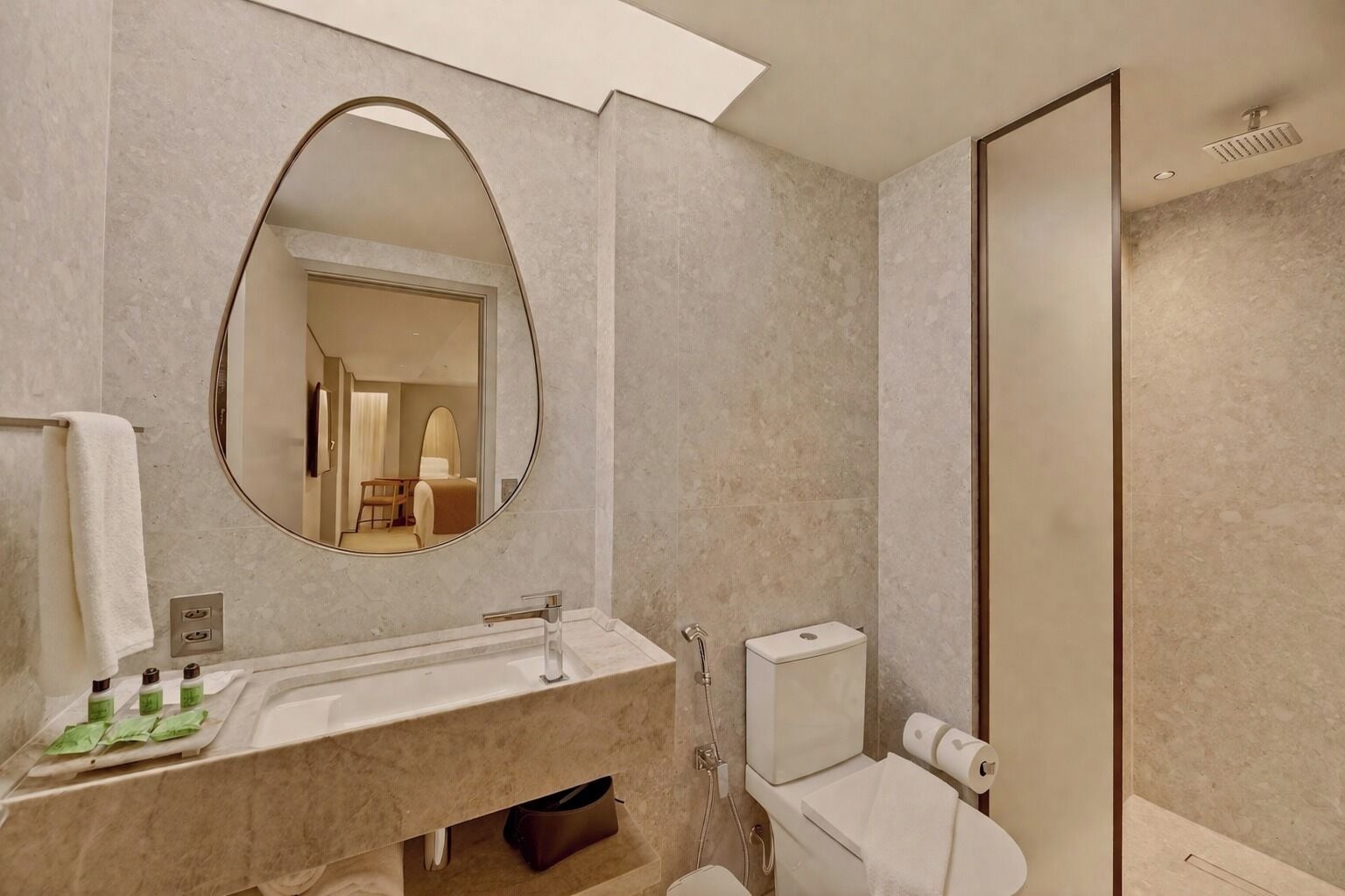A modern bathroom with a large mirror, a sink, a toilet, and a shower.
