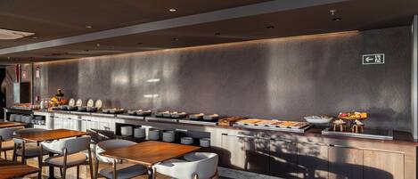A modern restaurant with a long counter, multiple seating areas, and a wall-mounted menu display.