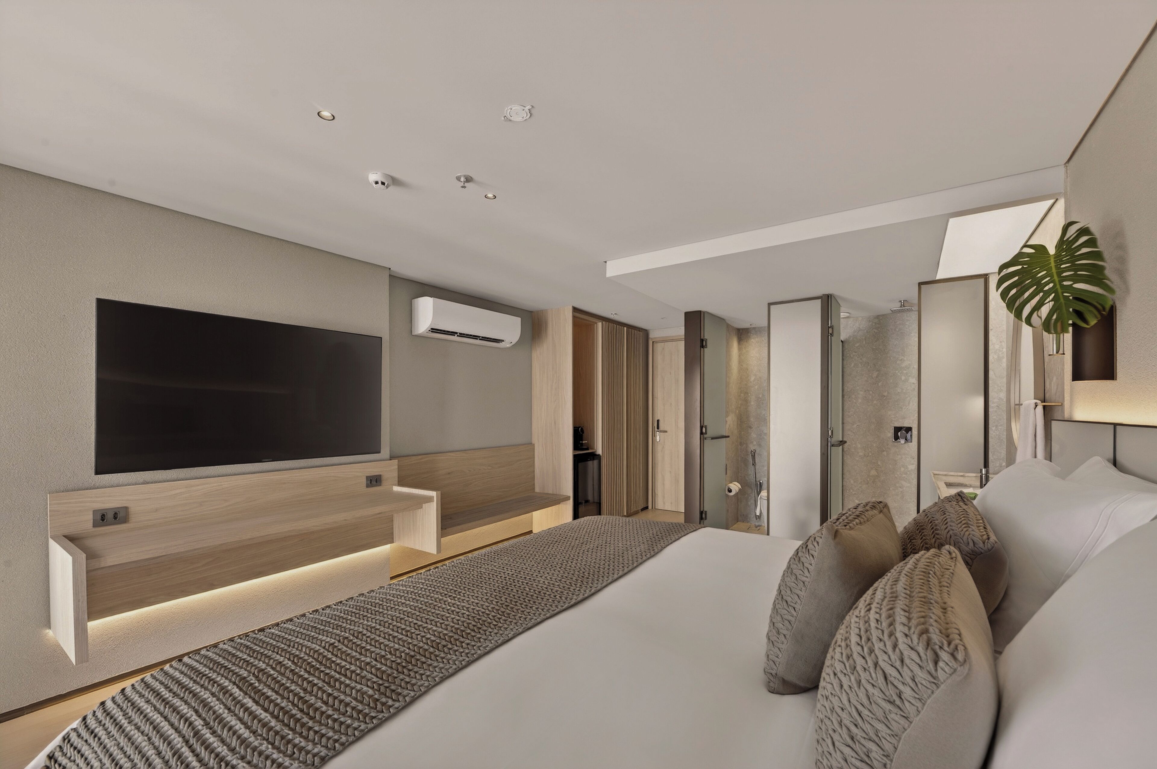 Een moderne hotelkamer met een groot bed, een flatscreen televisie aan de muur, een ingebouwde airconditioning en een groot raam met uitzicht op de stad.