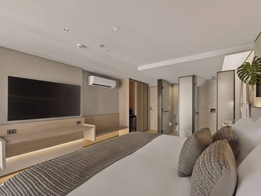 Een moderne hotelkamer met een groot bed, een flatscreen televisie aan de muur, een ingebouwde airconditioning en een groot raam met uitzicht op de stad.