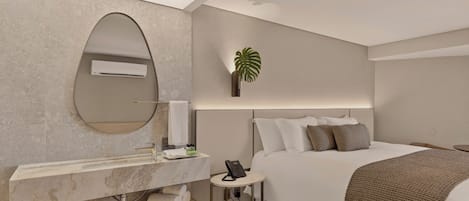 Una camera d'albergo moderna con un letto grande, un comò integrato con specchio, un piccolo comodino con un telefono e una pianta in vaso.