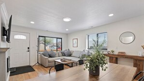 Een moderne woonkamer met een bank, salontafel en een eethoek met een houten tafel.