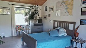 A bedroom with a bed, a dresser, a map on the wall, and a window with curtains. - Charming little house in the countryside (La Garnache)