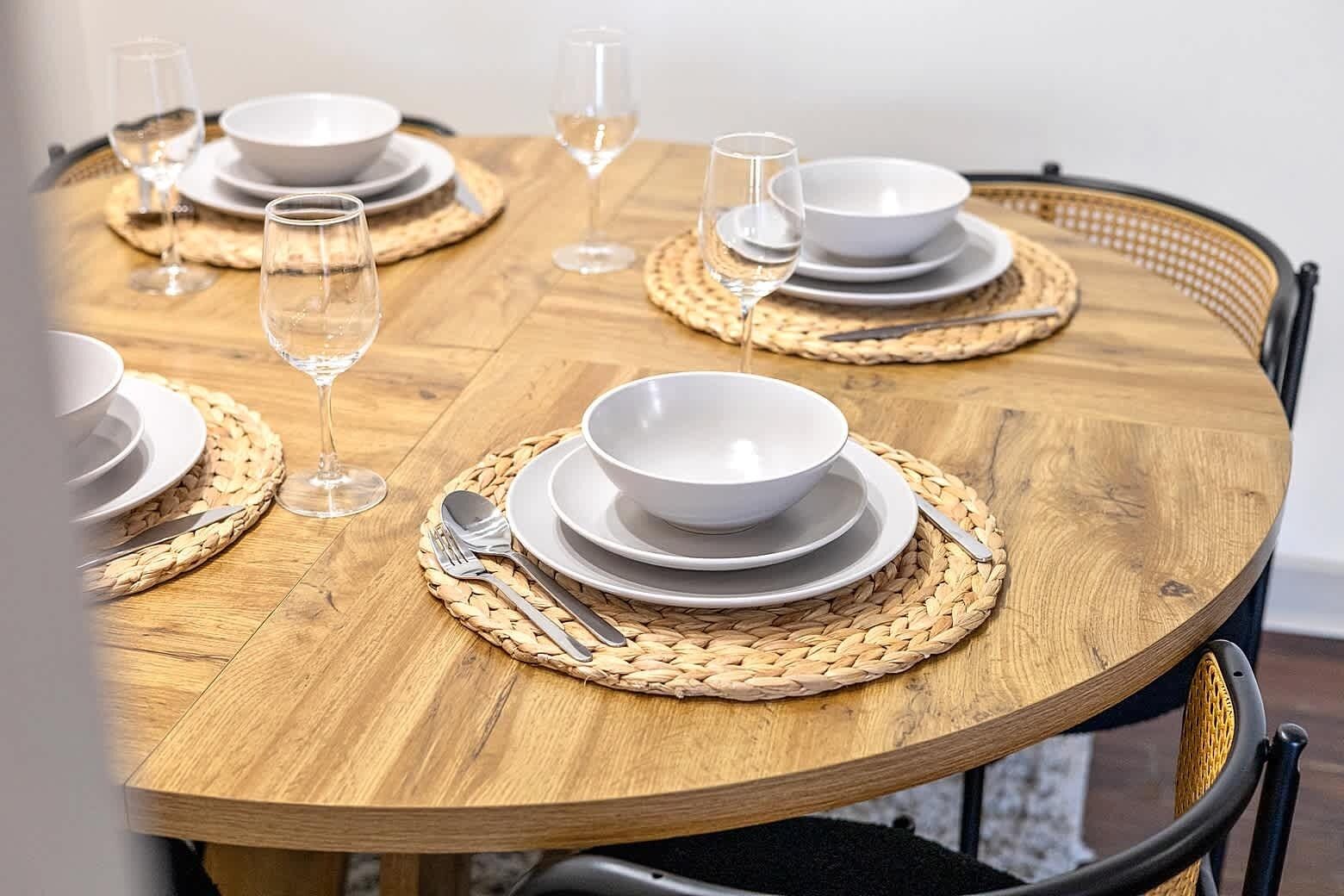 Inviting dining area with a round wooden table set for four, perfect for shared meals or casual conversations. Conveniently located near the kitchen, offering a cozy spot to dine without a formal dining room layout.