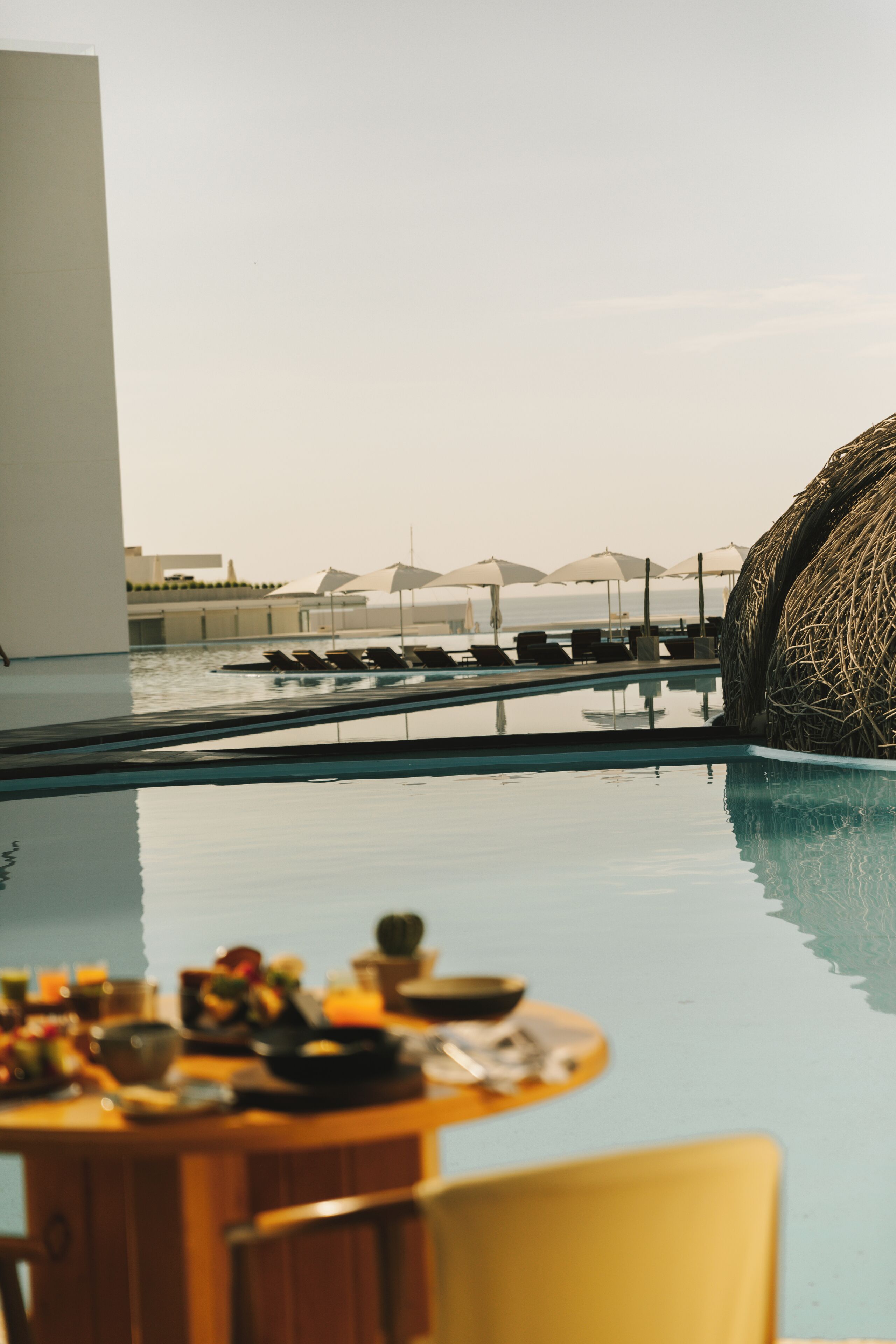 A poolside dining area with a view of the sea and umbrellas.