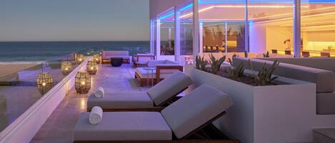 A modern outdoor lounge area with seating and a view of the ocean.