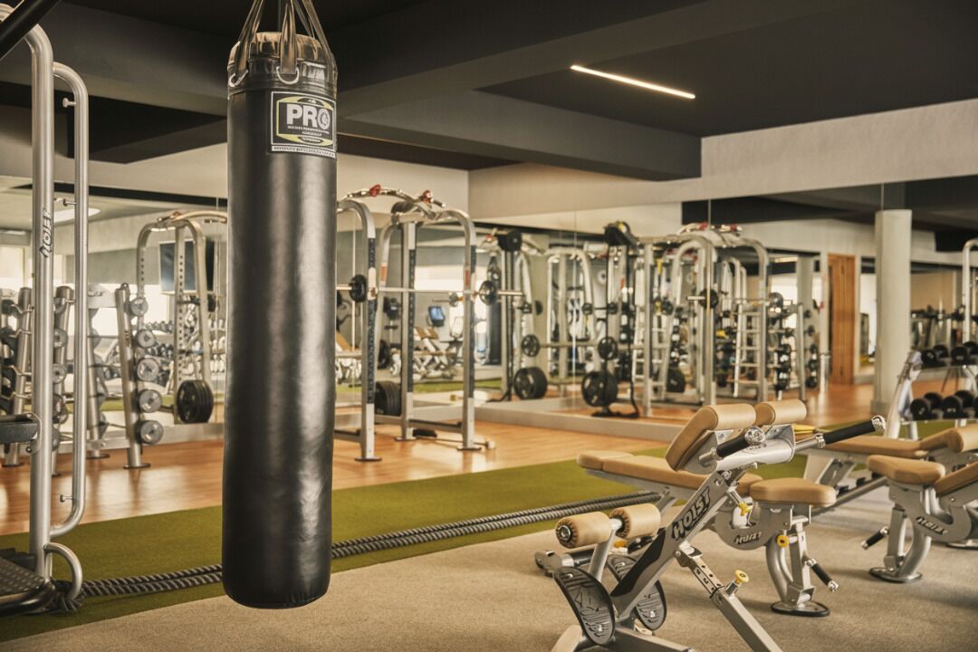 Une salle de sport équipée de divers appareils d’entraînement, notamment un sac de frappe, des appareils de musculation et des poids libres.