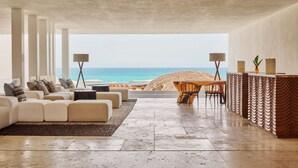 Un salon moderne doté d’un grand canapé, d’un coin repas et offrant une vue sur la plage.